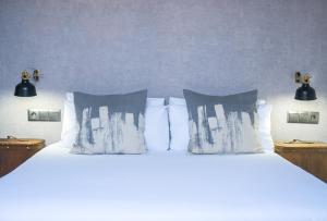 马拉加The Lights City Rooms的卧室内的一张带白色床单和枕头的床