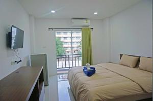 华欣AD住宿公寓的一间卧室配有一张带书桌的床和窗户。