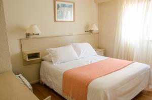 埃斯特角城日落海滩酒店 的卧室配有一张带白色床单的大床和窗户。