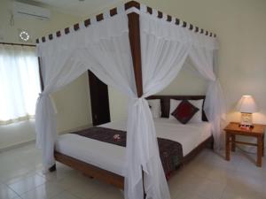 乌鲁瓦图宾津家庭简易别墅酒店的卧室配有带白色窗帘的天蓬床