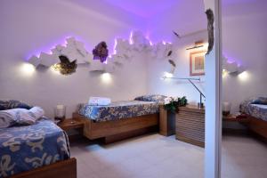 波尔图圣保罗Residence L'Ea di Lavru - Appartamenti Mono-Bilo-Trilocali的一间设有两张床的客房,墙上有紫色的灯光
