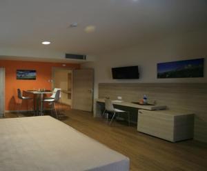 圣弗朗西斯科尔坎姆都灵机场公寓式酒店的一间设有桌椅的房间和墙上的电视