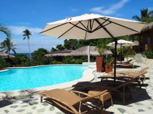 安达神奇海洋潜水度假村的游泳池旁配有椅子和遮阳伞