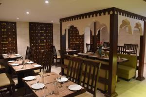 斋浦尔Jaipur Hotel New - Heritage Hotel的一间在房间内配有桌椅的餐厅