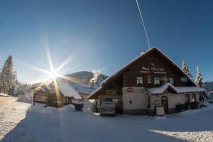 哈拉霍夫普劳科膳食公寓的雪中的一个滑雪小屋,后面有太阳