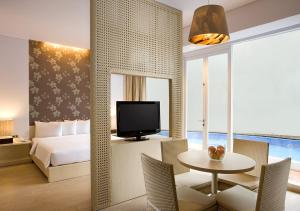 邦加槟港三提卡邦加酒店的一间卧室配有一张床、一张桌子和一台电视。