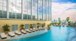 马尼拉Winford Resort and Casino Manila的酒店游泳池设有躺椅,酒店大楼