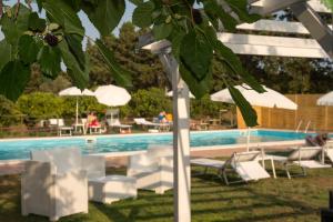 卡塔尼亚Sicily Country House & Beach的游泳池旁设有白色椅子和遮阳伞的游泳池