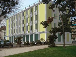 维琴察坎普玛泽欧酒店的一座黄色和白色的大建筑,前面有树木