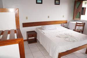 ItajuípePousada Do Bosque的一间卧室配有一张带木制床头板的床