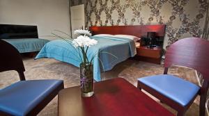 赫鲁迪姆Residence Arx & Wellness的一间卧室配有一张床,一个花瓶摆放在桌子上