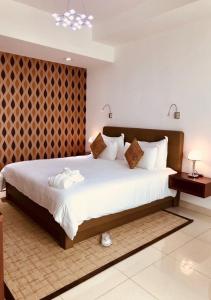 布拉柴维尔Pefaco Hotel Maya Maya的一间卧室配有一张带白色床单的大床