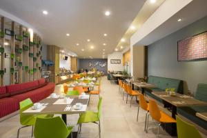 北加浪岸Khas Hotel Pekalongan的餐厅设有桌子和五颜六色的椅子和桌面