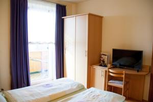 沃尔夫斯堡Gasthof Pension Zoller的一间卧室设有一张床、一台电视和一个窗口。
