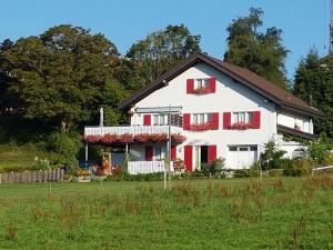 Les Breuleuxappartement "bellevue"的白色的房子,有红色百叶窗和院子
