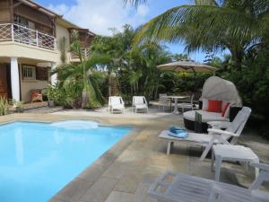 格兰高伯Villa Kreola的房屋旁的游泳池配有椅子和遮阳伞