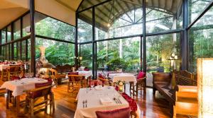 谭伯连山彼得斯热带雨林住宿加早餐旅馆的餐厅设有桌椅和大窗户。
