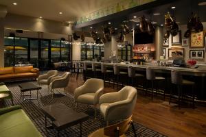 休斯顿Hotel ZaZa Houston Memorial City的餐厅内的酒吧,配有椅子和吧台