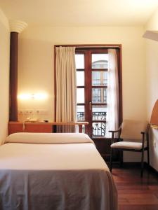 卢安科广场一号酒店的一间卧室配有一张床、一张书桌和一个窗户。