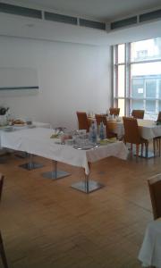 格赖夫斯瓦尔德Hôtel Galerie的一间设有白色桌椅和窗户的用餐室