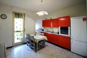 贝内瓦吉恩纳Bene Vagienna Holiday House的厨房配有红色橱柜、桌子和冰箱
