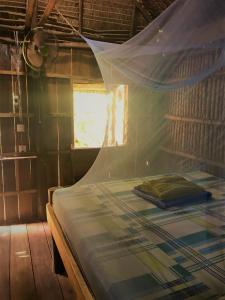 高龙撒冷岛懒人旅舍的一间卧室配有一张带蚊帐的床