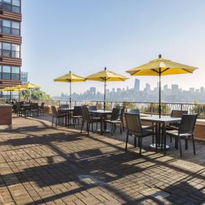 霍博肯Global Luxury Suites at Hoboken Waterfront的一排带黄伞的桌椅