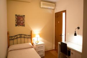 卡萨韦梅哈Pensión y apartamentos El Taxi的一间卧室配有一张床和一张带台灯的书桌