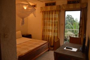 吉塞尼Ubumwe Hotel的一间卧室设有一张床、一个窗口和一张桌子