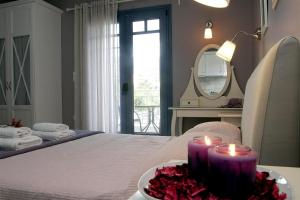 特里佐尼亚Boutique Hotel Iasmos的一间设有一张带两张蜡烛和镜子的床的房间