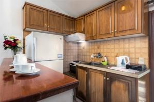 波罗斯Areti Apartments的厨房配有木制橱柜和白色冰箱。