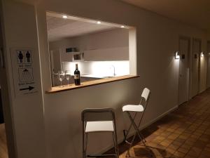 博雷Klintholm Marina Park Cabins的厨房配有两把椅子和一个带一瓶葡萄酒的吧台