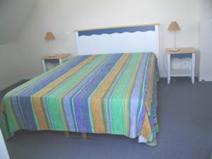 洛克马里亚Maison avec vue sur mer dans Résidence Marie Galante的一间卧室配有一张带彩色条纹床罩的床