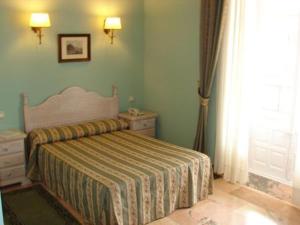 特鲁希略维多利亚酒店的一间卧室配有一张床、一个梳妆台和一扇窗户。