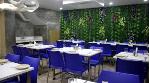 古瓦哈提Hotel Shreemoyee Inn - Kamakhya Temple的餐厅设有白色桌子、蓝色椅子和绿色的墙壁