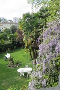 波城Villa Dampierre的紫色花卉花园内的桌椅