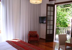 彼得罗波利斯Hotel Casablanca Koeler的一间卧室配有一张床、一把椅子和电视