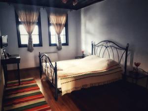 多布里奇Khan Staria Dobrich Family Hotel的一间卧室设有一张床和两个窗户。