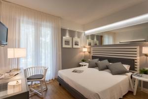 利尼亚诺萨比亚多罗Suite Erica Lignano Hotel的一间卧室配有一张大床、一张桌子和一把椅子