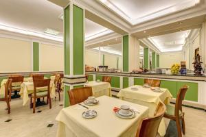 罗马洛吉亚酒店的餐厅设有桌椅和绿色的墙壁