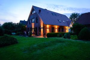 MinsenFerienwohnungen Hensel的绿色草坪上一座带深色屋顶的房屋