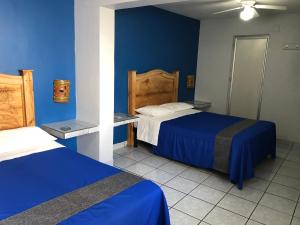 瓜达拉哈拉圣胡安酒店的一间卧室设有两张床和蓝色的墙壁
