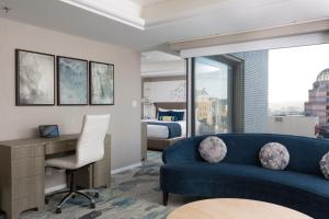 旧金山旧金山日航酒店的客厅配有蓝色的沙发、书桌和床。