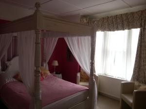 海斯廷斯1066塔楼旅馆的一间卧室设有天蓬床和窗户。
