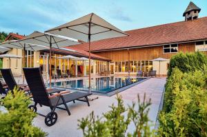 博登迈斯博尔霍夫维塔尔康体酒店的一座带椅子和遮阳伞的游泳池位于一座建筑旁边
