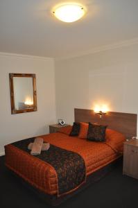 奥古斯塔港奥古斯塔庭院汽车旅馆的一间卧室配有一张带镜子的大型橙色床