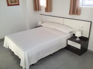 洛帕莞普迪卡旅馆的一间卧室配有一张白色大床和床头柜