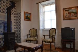 洛里加Casa da Ponte do Arrocho的客厅配有两把椅子和电视