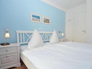 奥斯赛拜-塞林Haus Möwe - Apt. 013的卧室配有白色的床和蓝色的墙壁