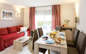 萨拉瓦Résidence Odalys Les Hauts de Salavas的客厅配有桌子和红色沙发